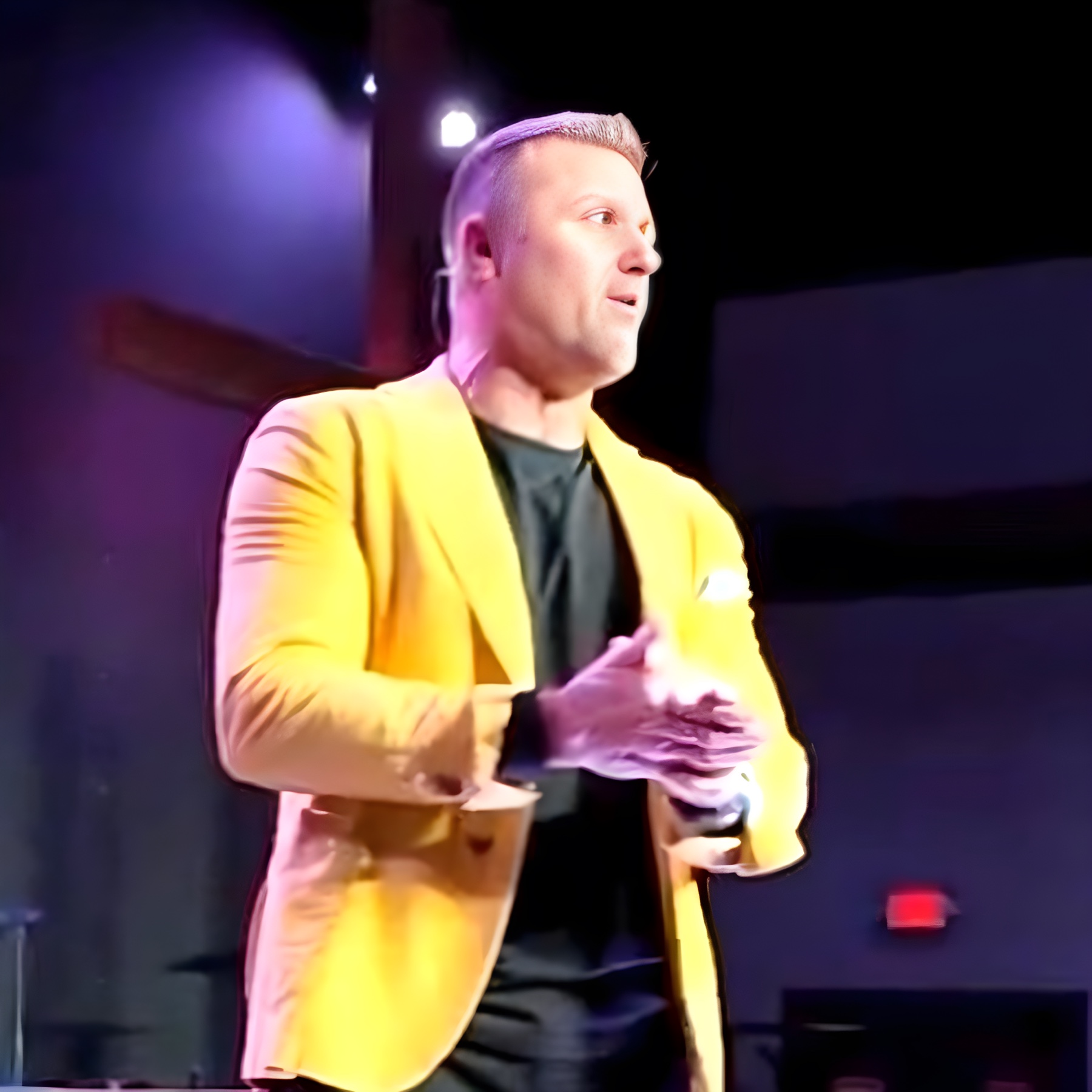 Jeremy Deeble on stage in a yellow blazer, mid-keynote